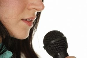 Woman's Mouth to Microphone Close-up --- Image by © Ocean/Corbis